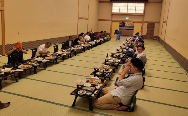 広い座敷で、それぞれの御膳を前に社員が座っている